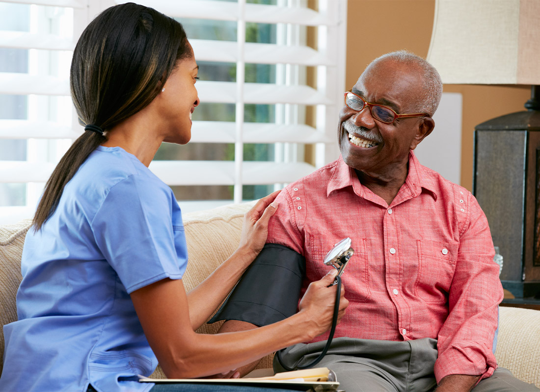 Medicare - Male Senior Getting His Blood Pressure Checked at Home by Health Care Nurse